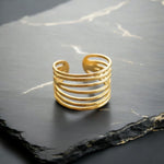 Load image into Gallery viewer, Gold ring with multiple loops on a dark stone surface
