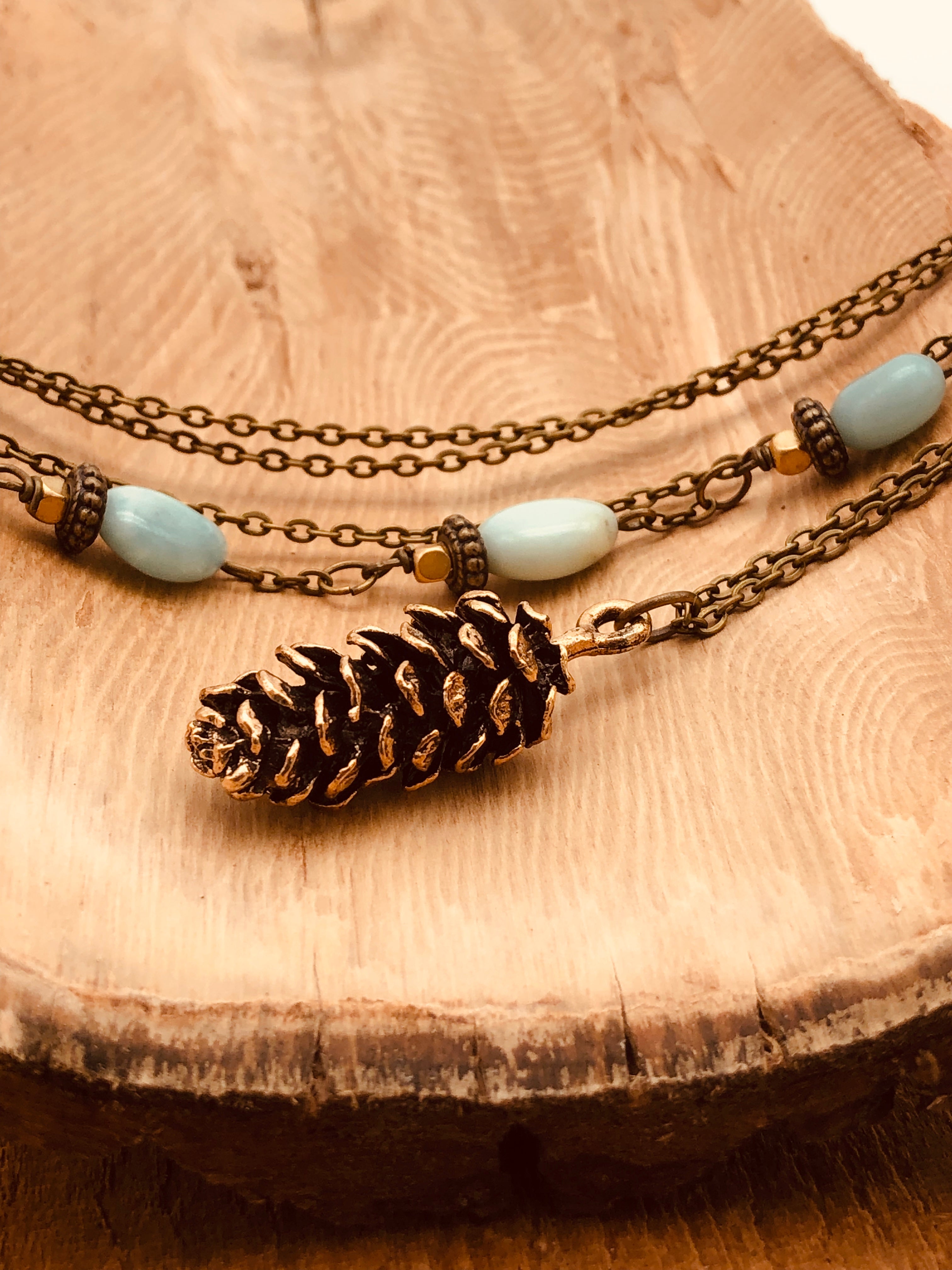 Long bronze necklace with realistic pinecone pendant and asymmetrical stones on chain. 